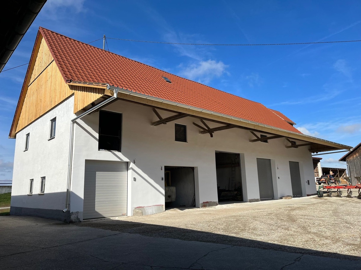 Weißes Bauernhaus mit neuem roten Ziegeldach und Holzverkleidung