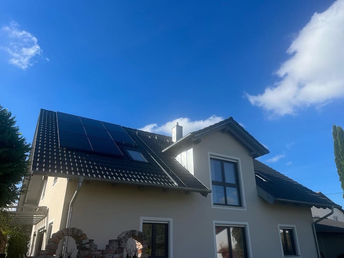 Haus mit dunkelgrauem Ziegeldach, Solarzellen und Gerüst